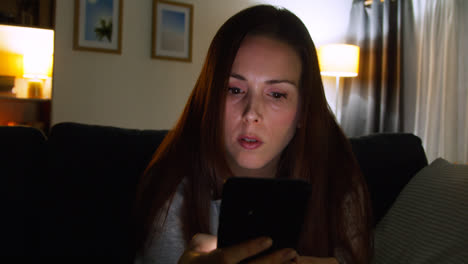 Anxious-Woman-Sitting-On-Sofa-At-Home-At-Night-Looking-At-Mobile-Phone-Concerned-About-Social-Media-Or-Bad-News-5